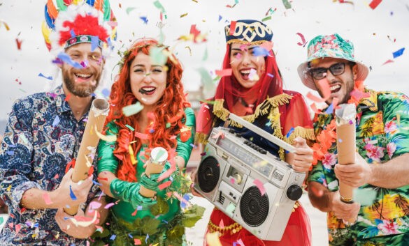 Happy dressed people celebrating at carnival party throwing confetti Focus on left girl hands